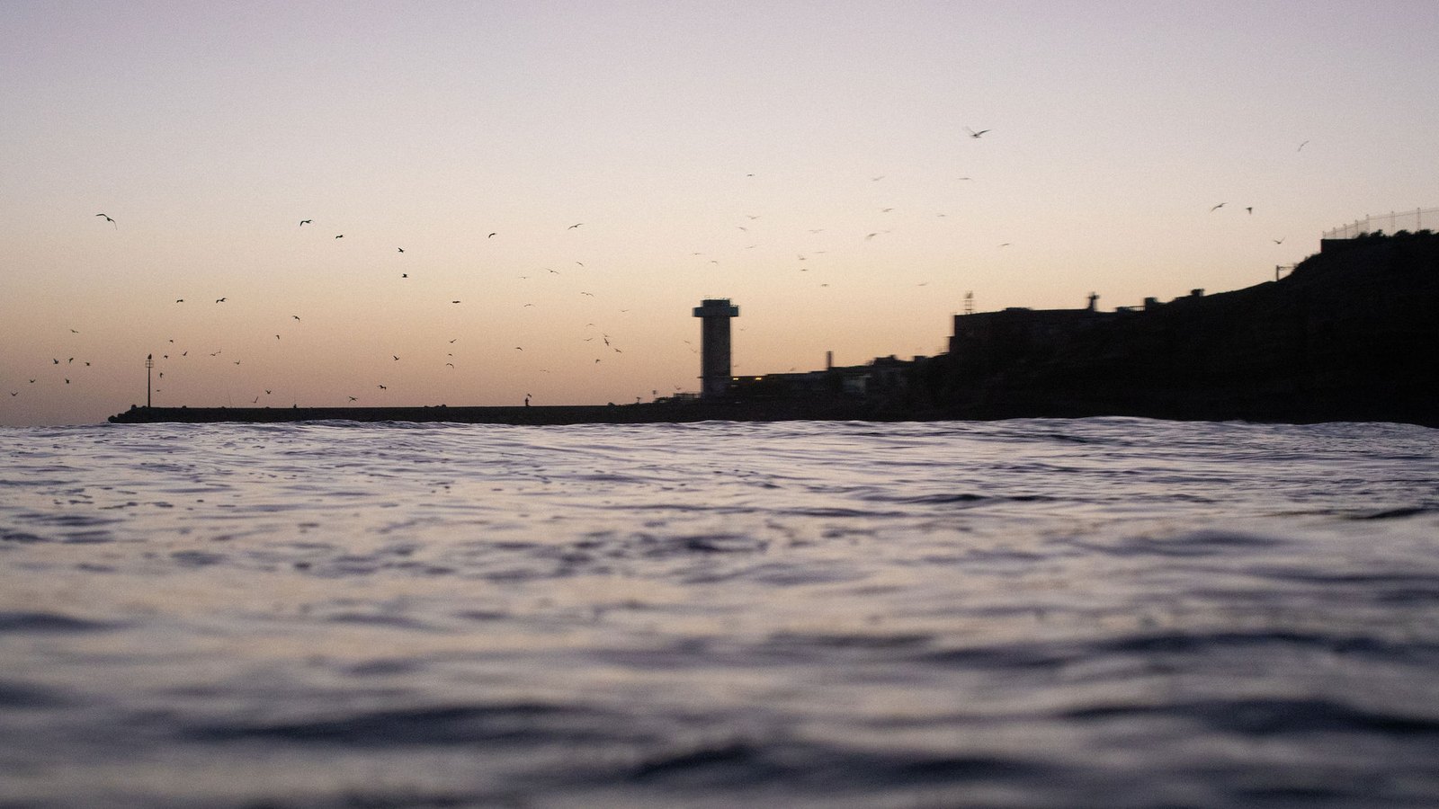 La pointe d'Imsouane et son phare au crépuscule, les oiseaux au-dessus de l'eau